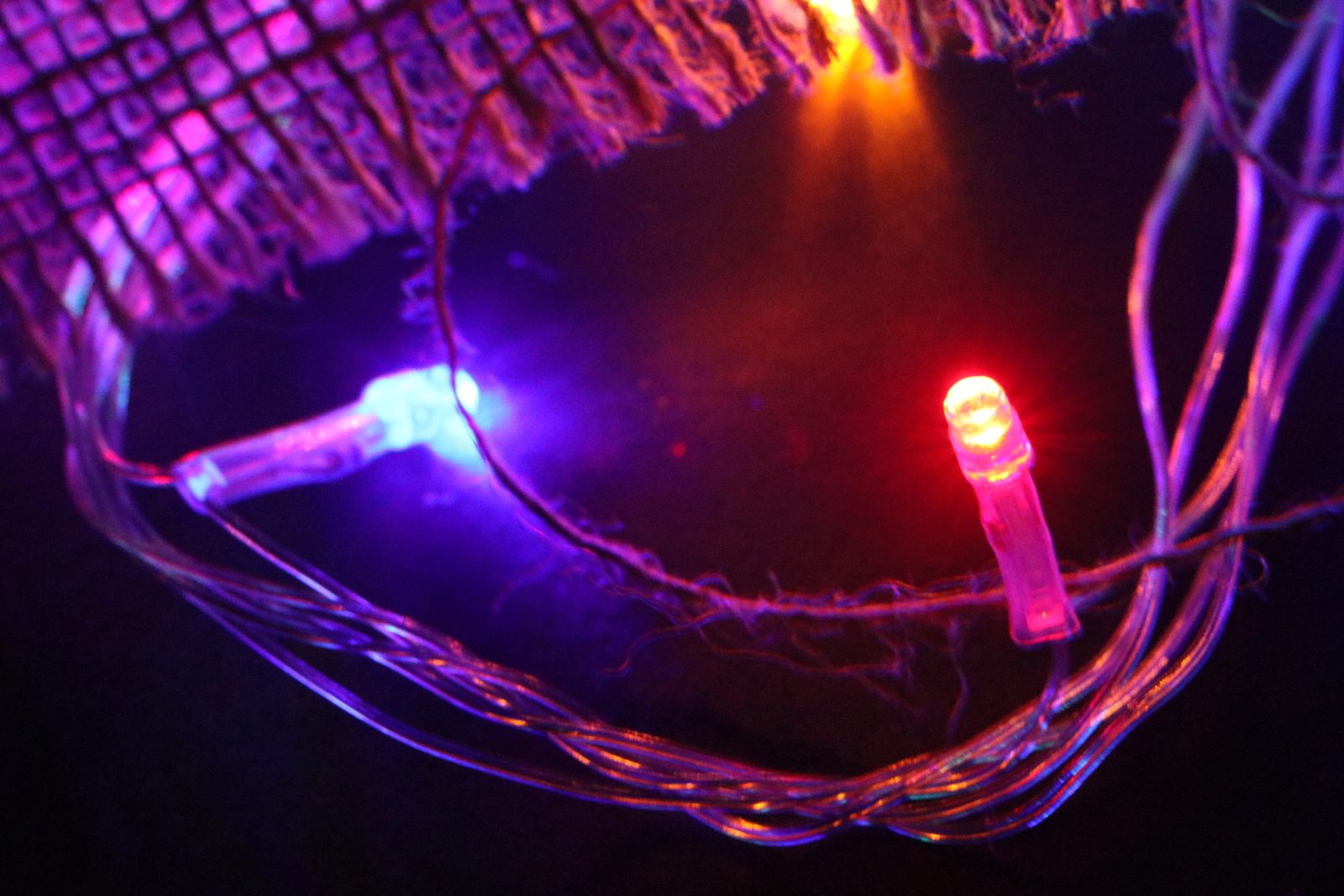 Fairy lights glowing red and blue through burlap.