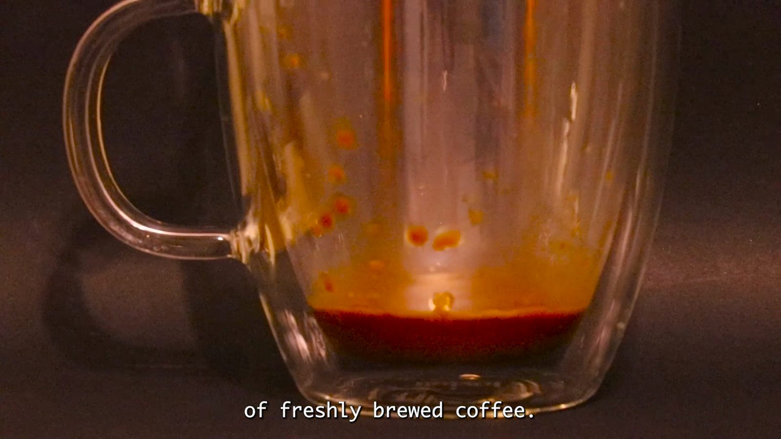 Film still: an almost empty glass coffee mug with the subtitle: of freshly brewed coffee.